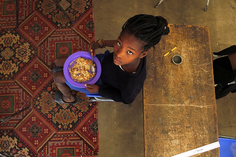 In this photo taken on Thursday, Nov. 14, 2019, children share a meal they received from a government sponsored feeding scheme at the Delta Primary School in Vosburg, South Africa. The worst drought some farmers have seen in decades is affecting much of southern Africa. The United Nations says more than 11 million people now face crisis levels of food insecurity. (AP Photo/Denis Farrell)