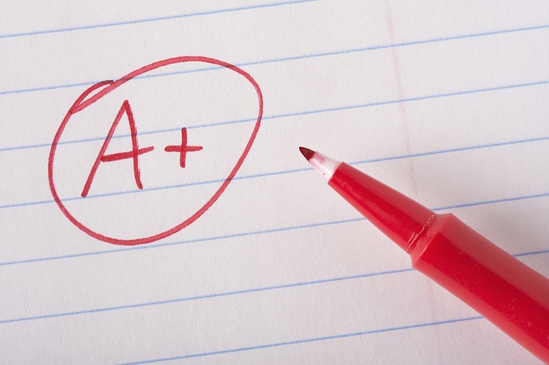 A plus (A+) grade written in red pen on notebook paper with the pen sitting there. report card tile smart tile school tile paper a grade tile / Getty Images

