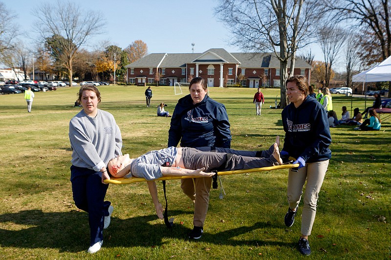 Staff photo by C.B. Schmelter / Hannah Green, left, Elizabeth Cope and Alexandria Reuter carry a simulated victim during a mass casualty drill outside of the School of Nursing on the campus of Lee University on Wednesday, Nov. 20, 2019 in Cleveland, Tenn. Green, a junior nursing major, was acting as an emergency medical technician. Both Cope and Reuter are first-year masters students in the athletic training program. The simulated mass casualty drill allows students to practice their clinical skills in response to a surge of patients coming into a health care facility for treatment of their injuries under accelerated stress levels.