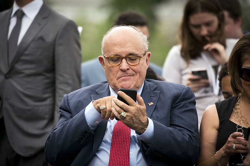 File photo by Doug Mills of The New York Times / Rudy Giuliani, President Donald Trump's personal lawyer, uses his smartphone during a ceremony at the White House on May 30, 2018. American officials have expressed wonderment that Giuliani was running his "irregular channel" of diplomacy over open cell lines and communications apps penetrated by the Russians.