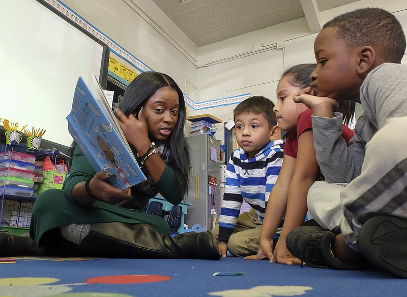 Staff photo by Tim Barber/ Dupont Elementary School teacher Brenda Morris reads to Alex Perez Garcia, center, Ashley Perez and Jace Coonrod Friday in the "Rich Lit Initiative" effort to put books in the hands of young readers.