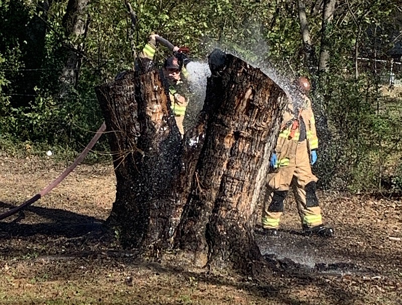 Chattanooga firefighters work Monday afternoon to extinguish a large tree stump in the backyard of a home on the 3000 block of Wheeler Avenue where a disabled veteran received serious burns while helping his neighbor with yard work.