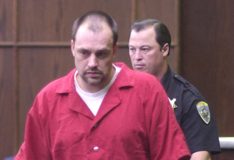 Convicted murderer Leroy Hall Jr. is taken by court officer Jim Pickett, right, into Judge Steve Bevil's courtroom in leg irons, chains, and handcuffs in 2002. / Staff file photo