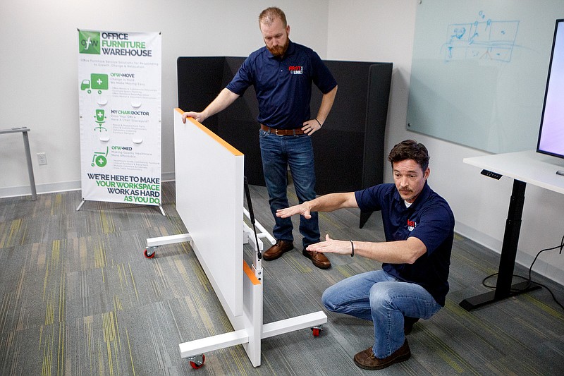 Staff photo by C.B. Schmelter / First Line Furniture President Rich Trubacek, right, and Vice President AJ Unger demonstrate their bulletproof desk for the Times Free Press from Office Furniture Warehouse on Thursday, Nov. 21, 2019 in Chattanooga, Tenn.