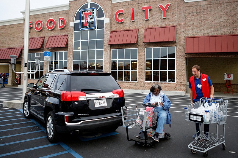 Staff photo by C.B. Schmelter / Chattanooga FC Game Day Director Peter Woolcock, right, helps bring groceries to Iretha Gardner's car during the 13th annual Celebrity Bagging Event at the Food City in St. Elmo neighborhood on Tuesday, Nov. 26, 2019 in Chattanooga, Tenn. This year's annual fundraising event, held in conjunction with the United Way, helped to benefit the Times Free Press Neediest Cases appeal. Local celebrities volunteered their time to bag groceries and shoppers who wished to do so contributed to the United Way at checkout.