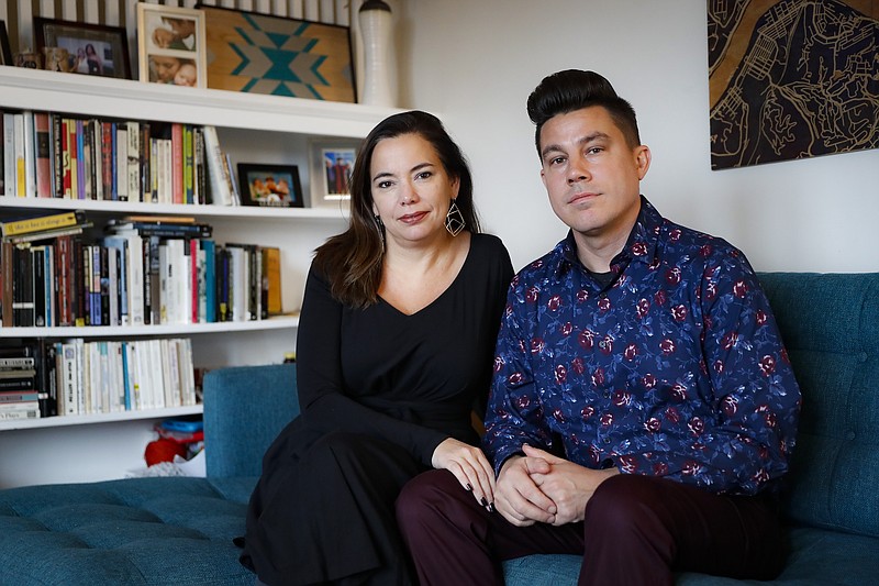 Cincinnati couple Bryan Wright and Farrah Jacquez pose for a photograph at their home, Tuesday, Nov. 26, 2019, in Cincinnati. Already polarized over Republican Donald Trump’s presidency, Americans are deeply split on a looming historic impeachment. Many families reflect the nation’s divisions, setting up heated holiday debates in households. Wright says "impeachment will definitely come up" as a divisive topic at his extended family's holiday meal. (AP Photo/John Minchillo)