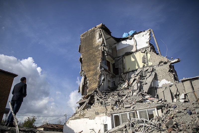A man looks at a damaged building after an earthquake in Thumane, western Albania, Wednesday, Nov. 27, 2019. Overnight, authorities said four more people had been confirmed dead, and one more death was reported early Wednesday afternoon, raising the death toll to 26, while more than 650 people were injured in the magnitude-6.4 quake that struck the country's coastal cities. (AP Photo/Petros Giannakouris)