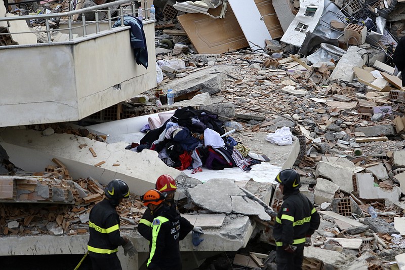 Italian rescuers stand in front of a collapsed house of Lala family in Durres, western Albania, Thursday, Nov. 28, 2019. Hopes were fading Thursday of finding anyone else alive beneath the rubble of collapsed buildings in Albania two days after a deadly quake struck the country's Adriatic coast, with the death toll increasing to 40 after more bodies were pulled from the ruins. (AP Photo/Hektor Pustina)