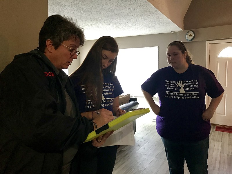 Staff photo by Sabrina Bodon / From left, Regina Dorsey, Kayla Roerdink and Sarah Yarbrough go over fire safety tips while installing a fire alarm in a Rossville home.