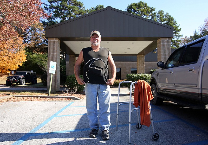 Staff photo by Erin O. Smith / Mike Ward, 47, shows off the vest his sister helped make him for carrying batteries and parts of his left ventricular assist device, or LVAD, in front of Palliative Care Services Tuesday, November 19, 2019 off of Oakwood Drive in Chattanooga, Tennessee. "I like this one because my sister made it, plus I've gotten the sleeves cut off right here like Larry the Cable Guy to make it comfortable. I've got a white one that I'm saving for a special occasion," he said. The LVAD is what keeps blood flowing through Ward's body.