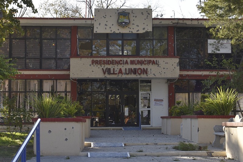 The City Hall of Villa Union is riddled with bullet holes after a gun battle between Mexican security forces and suspected cartel gunmen, Saturday, Nov. 30, 2019. At least 14 people were killed, four of them police officers, after an armed group in a convoy of trucks stormed the town, in Coahuila state, prompting security forces to intervene, state Gov. Miguel Riquelme Solis said. (AP Photo/Gerardo Sanchez)