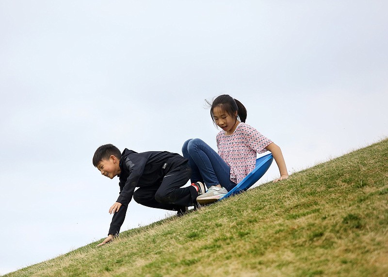 Tysen Kim, 8, topples off the front of a sled as he and his friend, Claire Kim, 11, slide down the hill at Renaissance Park Saturday, April 13, 2019 in Chattanooga, Tennessee. Due to the rain earlier in the day, their sled kept getting stuck on the side of the hill, which is what caused Tysen to be thrown forward. 