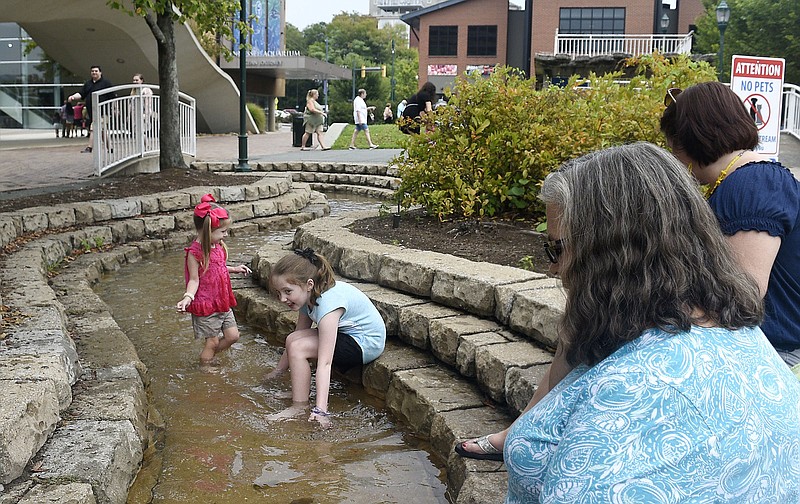 Staff Photo by Robin Rudd/ Children play in the stream in the plaza outside the Tennessee Aquarium. From back to front, Charlotte Smith and Audrey Smith play under the watch of their mother Amber Smith and grandmother Lou Ann Collier from Gadsden, Alabama.