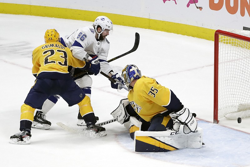 Tampa Bay Lightning right wing Nikita Kucherov (86), of Russia, scores the winning goal past Nashville Predators goaltender Pekka Rinne (35), of Finland, and Rocco Grimaldi (23) in overtime of an NHL hockey game Tuesday, Dec. 3, 2019, in Nashville, Tenn. The Lightning won 3-2. (AP Photo/Mark Humphrey)