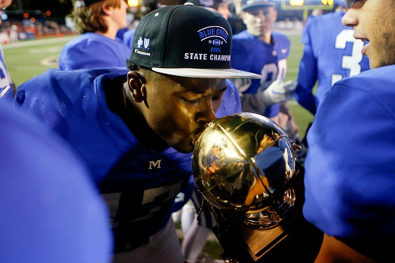 McCallie's DeAngelo Hardy kisses the state championship trophy Thursday night at Tennessee Tech's Tucker Stadium after the Blue Tornado beat Montgomery Bell Academy in the Division II-AAA BlueCross Bowl. / Staff photo by C.B. Schmelter