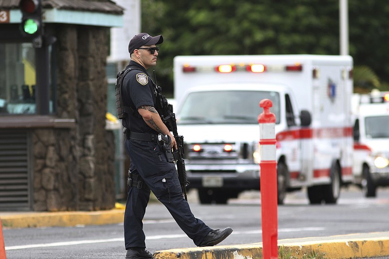 A security guard stands outside the main gate at Joint Base Pearl Harbor-Hickam, in Hawaii, Wednesday, Dec. 4, 2019. A shooting at Pearl Harbor Naval Shipyard in Hawaii left at least one person injured Wednesday, military and hospital officials said. Joint Base Pearl Harbor-Hickam spokesman Charles Anthony confirmed that there was an active shooting at Pearl Harbor Naval Shipyard. (AP Photo/Caleb Jones)
