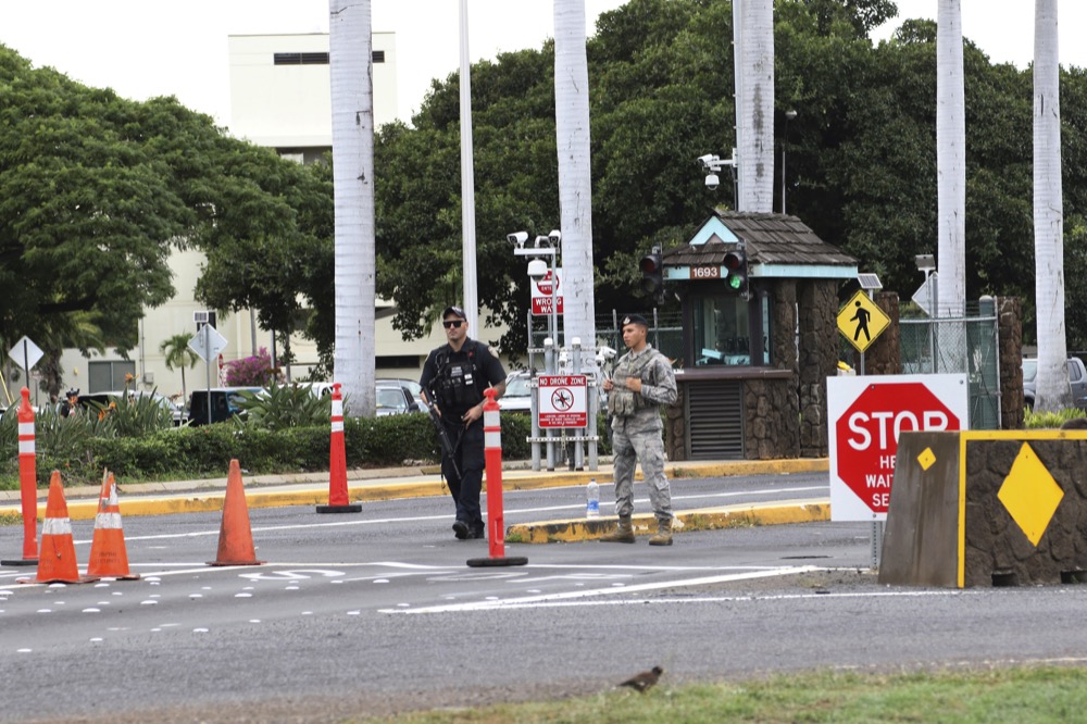 Security stand outside the main gate at Joint Base Pearl Harbor-Hickam Wednesday, Dec. 4, 2019, in Honolulu. A shooting at Pearl Harbor naval shipyard in Hawaii left at least one person injured Wednesday, military and hospital officials said. Joint Base Pearl Harbor-Hickam spokesman Charles Anthony confirmed that there was an active shooting at Pearl Harbor naval shipyard. The military tweeted that it began around 2:30 p.m. Queen's Medical Center spokesperson Cedric Yamanaka said the hospital was treating one patient but didn't give e details on their condition. (AP Photo/Caleb Jones)