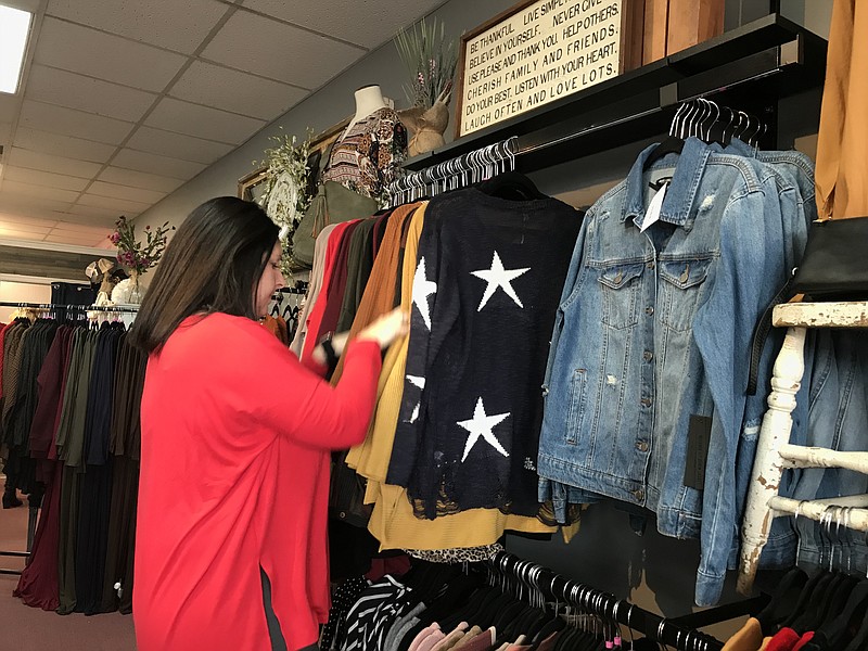 Staff photo by Sabrina Bodon / That's So Mimi boutique owner Kim "Mimi" Carlock organizes sweaters ahead of the holidays. Carlock opened Mimi's as a virtual store in 2017 and expanded into her physical location this year.