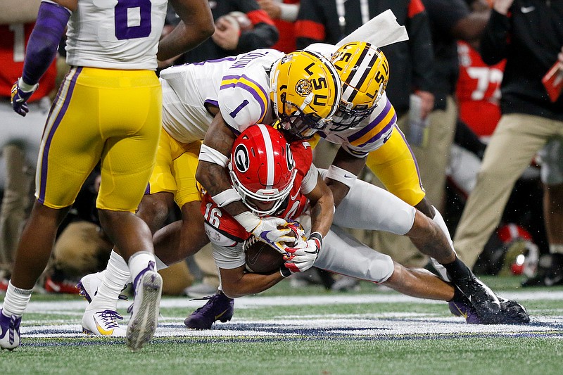 LSU cornerback Kristian Fulton (1) and safety Kary Vincent Jr. tackle Georgia wide receiver Demetris Robertson during the SEC title game Saturday at Mercedes-Benz Stadium in Atlanta. / Staff photo by C.B. Schmelter