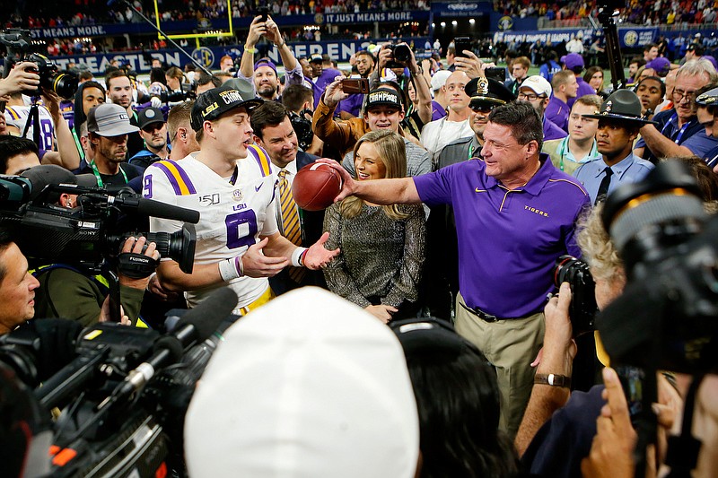 LSU coach Ed Orgeron hands a football to quarterback Joe Burrow after the Tigers beat Georgia 37-10 during the Southeastern Conference championship game Saturday night at Mercedes-Benz Stadium in Atlanta. / Staff photo by C.B. Schmelter