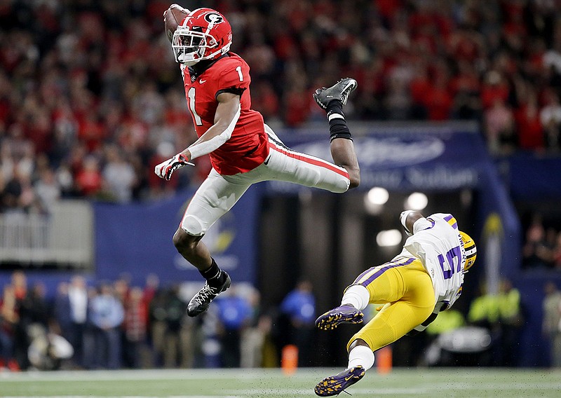 Georgia wide receiver George Pickens leaps over LSU safety Kary Vincent Jr. to convert a fourth down during Saturday's SEC title game at Mercedes-Benz Stadium in Atlanta. /  Staff photo by C.B. Schmelter