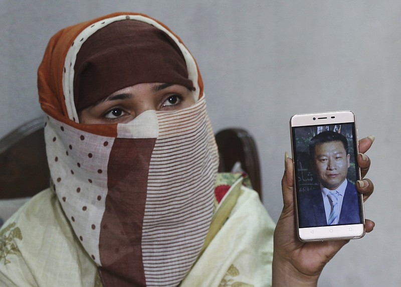 In this May 22, 2019 file photo, Sumaira a Pakistani woman, shows a picture of her Chinese husband in Gujranwala, Pakistan. Sumaira, who didn't want her full name used, was raped repeatedly by Chinese men at a house in Islamabad where she was brought to stay after her brothers arranged her marriage to the older Chinese man. The Associated Press has obtained a list, compiled by Pakistani investigators determined to break up trafficking networks, that identifies hundreds of girls and women from across Pakistan who were sold as brides to Chinese men and taken to China. (AP Photo/K.M. Chaudary, File)