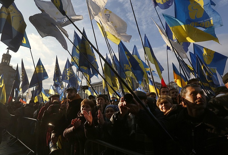 Ukrainians wave flags of various parties as they gather in central Kyiv, Ukraine, Sunday, Dec. 8, 2019. Several thousand people rallied Sunday in the Ukrainian capital of Kyiv to demand that the president defend the country's interests in this week's summit with Russia, Germany and France on ending the war in eastern Ukraine. (AP Photo/Efrem Lukatsky)