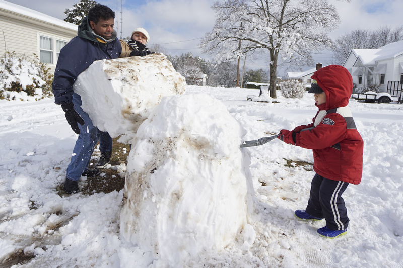 Staff Photo by Dan Henry / The Chattanooga Times Free Press- 2/26/15. Nathan Pillai and his wife Maria Pillai stack two huge snowball on top of each as their three-year-old son Samuel Pillai shapes the base in their Red Bank front yard Thursday morning, February 26, 2015.  An overnight winter storm dumped over half of a foot of snow on the Tennessee Valley area.