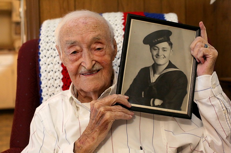 Staff photo by Erin O. Smith / Robert Rayburn poses for a photo with his Navy photo at his home Tuesday, October 15, 2019 in Chattanooga, Tennessee. Rayburn, a Navy veteran of World War II, took part in several battles.