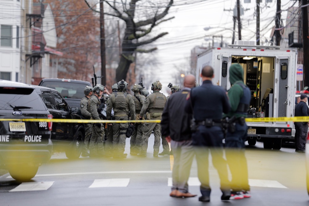 Police officers gather nearby the scene following reports of gunfire, Tuesday, Dec. 10, 2019, in Jersey City, N.J. (AP Photo/Seth Wenig)