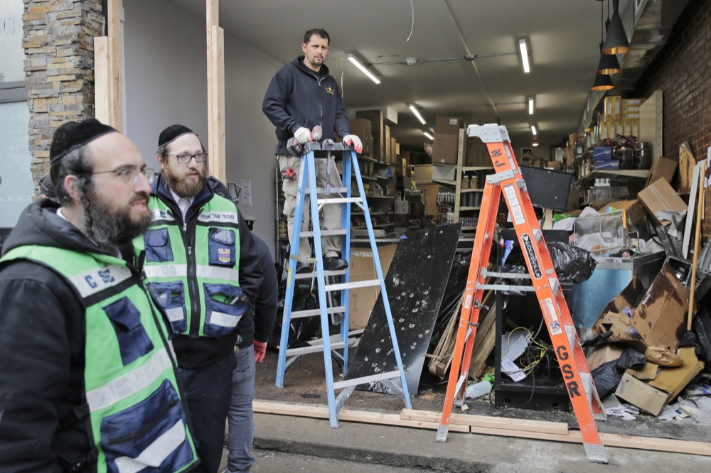 Bullet holes are seen on a piece of metal as people work to secure the scene of a shooting at a kosher supermarket in Jersey City, N.J., Wednesday, Dec. 11, 2019. The mayor of a New Jersey city says gunmen targeted the kosher market during a shooting that killed six people Tuesday. (AP Photo/Seth Wenig)