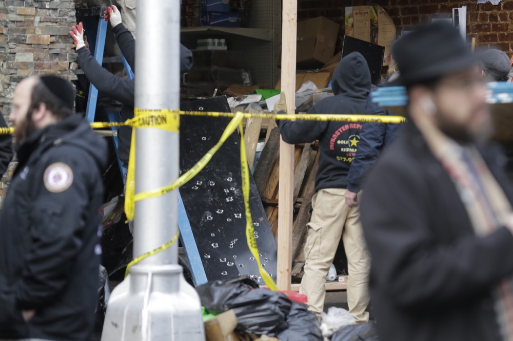Bullet holes are seen on a piece of metal as people work to secure the scene of a shooting at a kosher supermarket in Jersey City, N.J., Wednesday, Dec. 11, 2019. The mayor of a New Jersey city says gunmen targeted the kosher market during a shooting that killed six people Tuesday. (AP Photo/Seth Wenig)