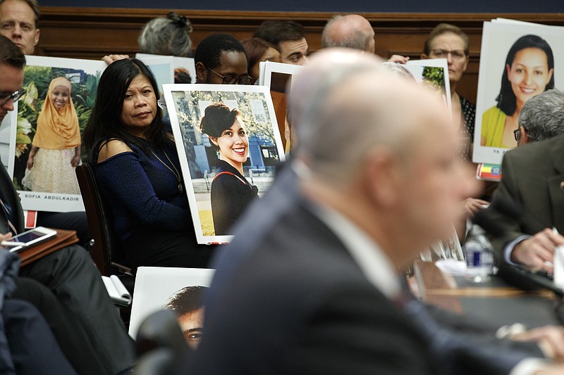 Family members of people who died in crashes of the Boeing 737 MAX hold photographs of their lost loved ones as FAA Administrator Stephen Dickson testifies during a House Transportation Committee hearing on the Boeing 737 MAX, Wednesday, Dec. 11, 2019, on Capitol Hill in Washington. (AP Photo/Jacquelyn Martin)