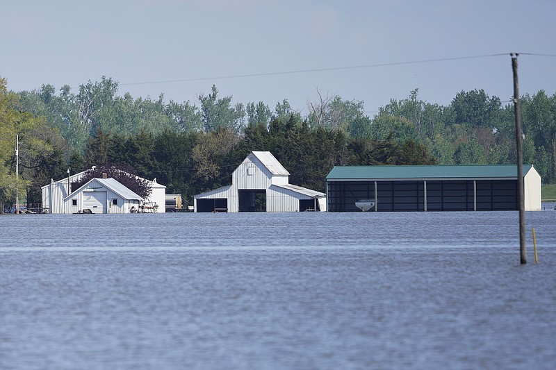 In this May 10, 2019, photo, farm buildings belonging to Brett Adams are surrounded by flood waters, in Peru, Neb. Adams had thousands of acres under water, about 80 percent of his land, this year. It split open his grain bins and submerged his parents' house and other buildings when the levee protecting the farm broke. (AP Photo/Nati Harnik)