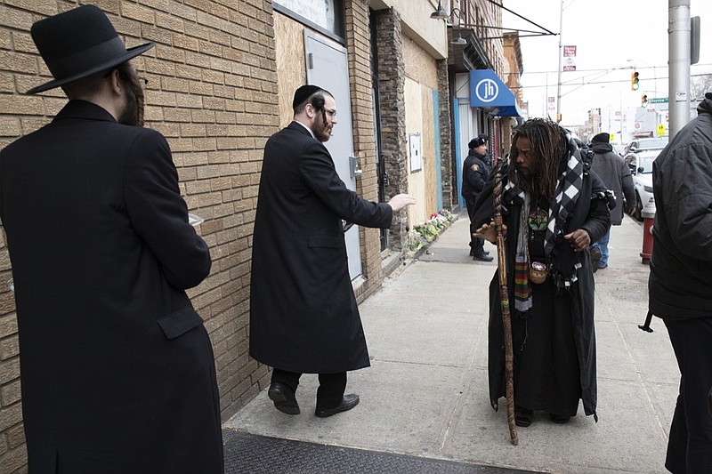 Robert McClain, right, offers condolences to two Jewish men, Friday, Dec. 13, 2019 in Jersey City, N.J. close to the site where three people and two gunmen were shot on Tuesday. New York Mayor Bill de Blasio called the incident a "premeditated anti-Semitic hate crime." (AP Photo/Mark Lennihan)