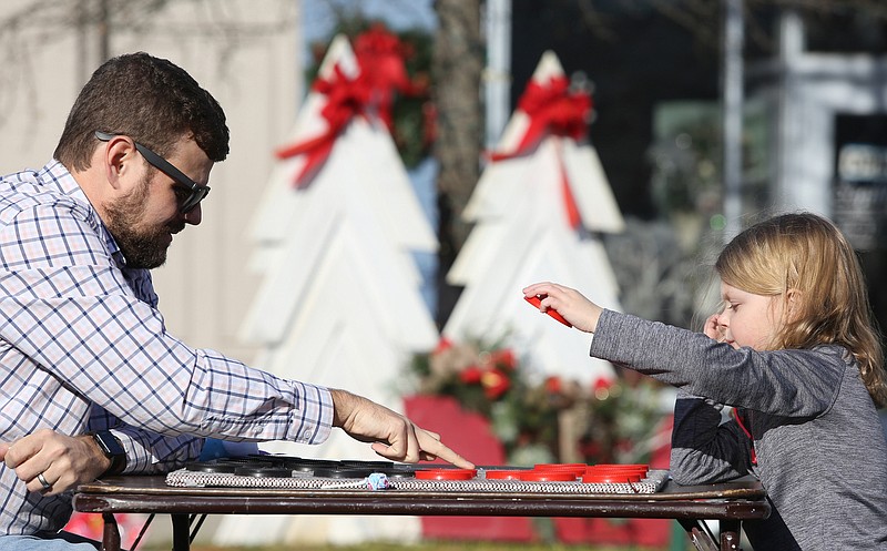 Staff photo by Erin O. Smith / Jeff Palmer and his 4-year-old daughter, Laura Hazel Palmer, play checkers during the Christmas in the Streets Block Party Saturday, December 14, 2019 in Chickamauga, Georgia. Laura was in the process of learning the rules of checkers.