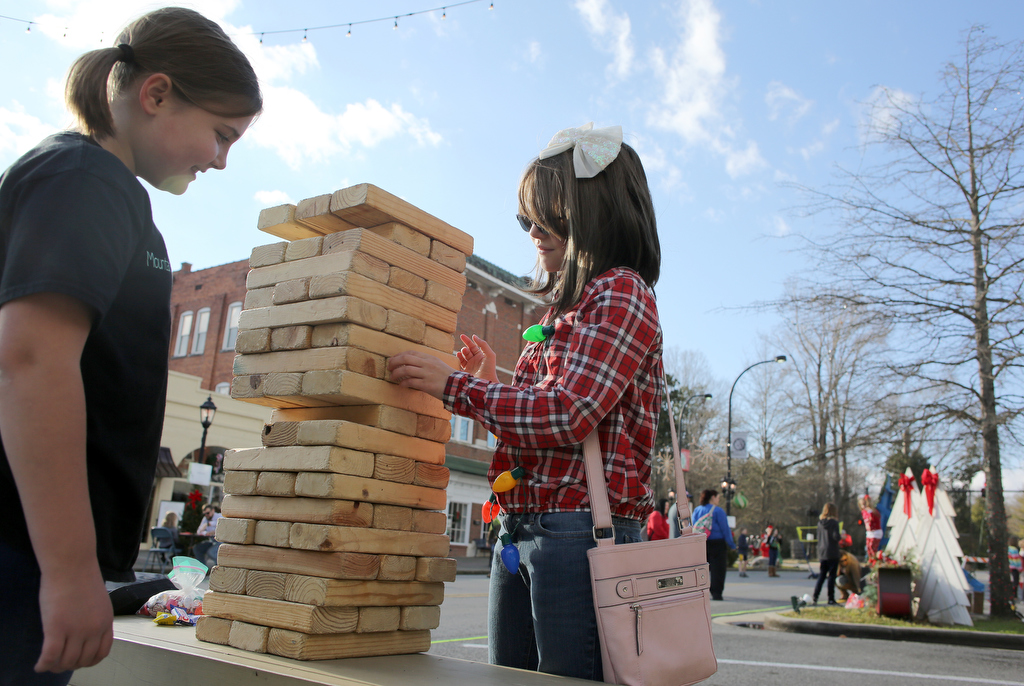 Staff photo by Erin O. Smith / Erin Grant, 10, and Halea Jackson, 10, play giant Jenga during the Christmas in the Streets Block Party Saturday, December 14, 2019 in Chickamauga, Georgia. There were games, pictures with Santa and Mrs. Claus, the Great Elf Hunt, a parade and a movie in the street.