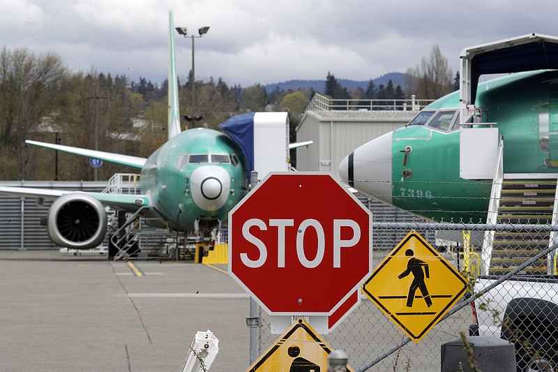 FILE - In this April 8, 2019, file photo Boeing 737 Max 8 jets are parked behind a stop sign indicating a traffic crossing at a Boeing Co. production facility in Renton, Wash. On Monday, Dec. 16, shares of Boeing are falling before the opening bell on a report that the company may cut production of its troubled 737 Max or even end production all together. (AP Photo/Elaine Thompson, File)