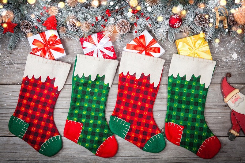 Christmas stocking hanging against wooden wall with gift presents and christmas decoration. Horizontal stocking tile christmas tile holiday sock package box tile gift gifts tile / Getty Images
