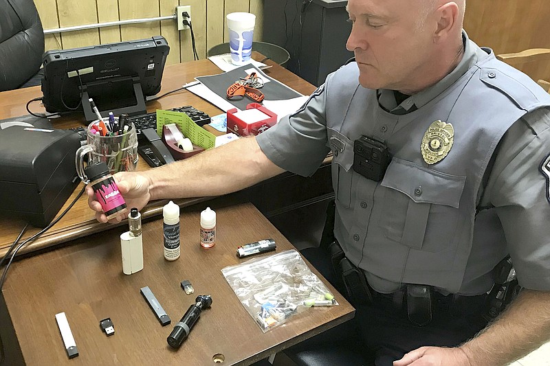 FILE - In this Sept. 23, 2019 photo, Bristol, Va., Police Officer Marlin Goff shows some of the vaping products he has confiscated from students at a high school. Congress is moving to pass the biggest new sales restrictions on tobacco products in more than a decade, with support in 2019 from two unlikely backers: Marlboro-cigarette maker Altria and vaping giant Juul Labs. (Tim Dotson/Bristol Herald Courier via AP)