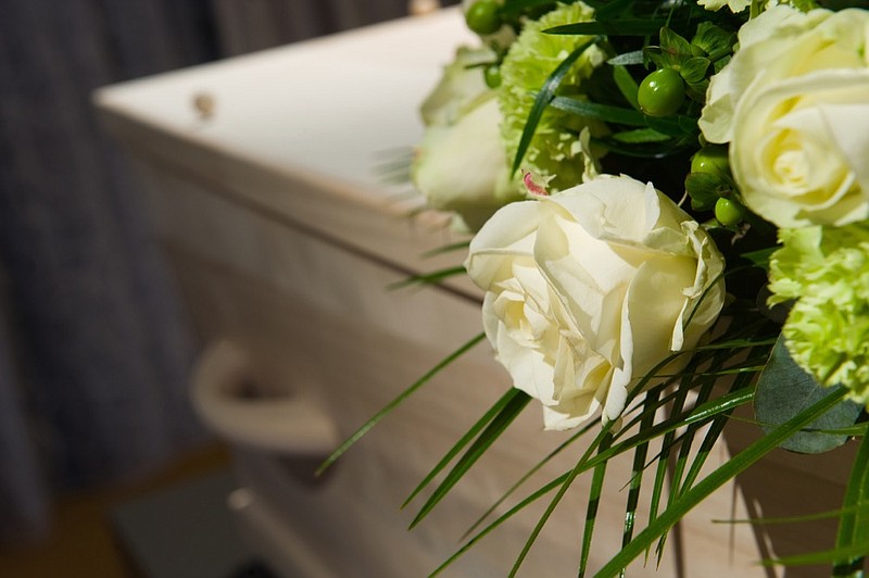 A coffin with a flower arrangement in a morgue cremation tile funeral coffin death tile crematorium / Getty Images
