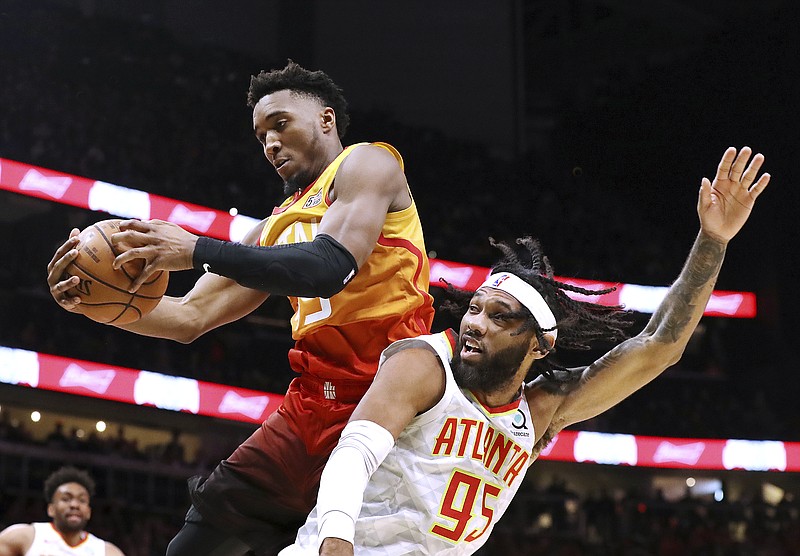 Utah Jazz guard Donovan Mitchell, top, grabs a defensive rebound over Atlanta Hawks guard DeAndre Bembry (95) during the second half of an NBA basketball game Thursday, Dec. 19, 2019, in Atlanta. (Curtis Compton/Atlanta Journal-Constitution via AP)