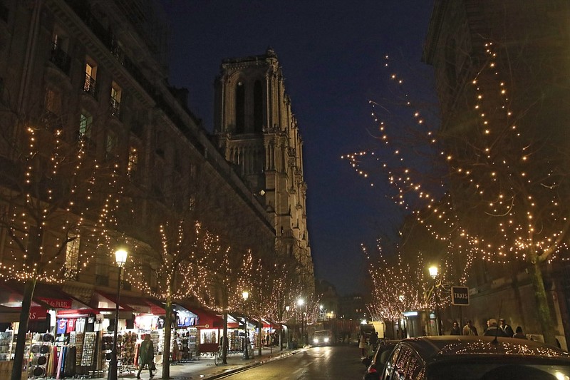 A shopper street decorated with Christmas lights leading to the Notre Dame Cathedral in Paris, Monday, Dec. 16, 2019. Notre Dame Cathedral has been newly illuminated last month since the April fire in 2019. (AP Photo/Michel Euler)