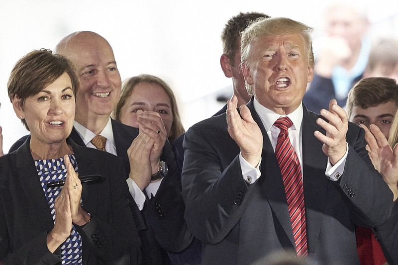 In this June 11, 2019 photo, President Donald Trump applauds next to Governors Pete Ricketts of Nebraska, second left, and Kim Reynolds of Iowa, left, in Council Bluffs, Iowa. An executive order by Trump giving states the right to refuse to take refugees is putting Republican governors in an uncomfortable position. They're caught between immigration hardliners who want to shut the door and others who believe helping refugees is a moral obligation. (AP Photo/Nati Harnik)