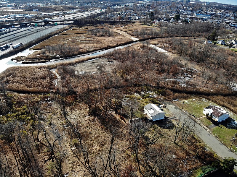 A flood-plain forest grows now where there used to be houses in the Watson Crampton neighborhood in Woodbridge, N.J., as seen from the air on Thursday, Dec. 5, 2019. The Heards Brook on the top meets the Woodbridge River on the left, which leads to the Atlantic Ocean. Homeowners here took buyouts through a program that purchases houses and demolishes them to remove people from danger and to help absorb water from rising sea levels due to climate change. (AP Photo/Ted Shaffrey)