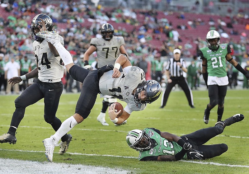 Central Florida quarterback Dillon Gabriel (11) leaps into the end zone for a touchdown over Marshall safety Nazeeh Johnson (13) during the Gasparilla Bowl NCAA college football game Monday, Dec. 23, 2019, in Tampa, Fla. (Stephen M. Dowell/Orlando Sentinel via AP)