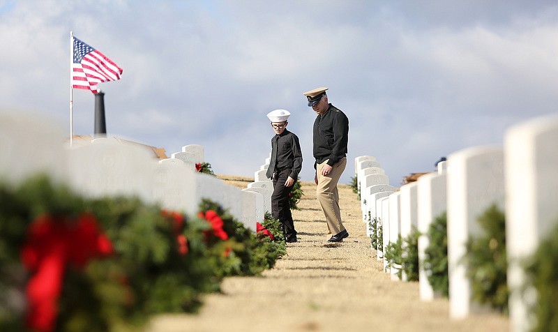 Staff photo by Erin O. Smith / Cullen Neudigate, 10, with the U.S. Navy Sea Cadets, and Scott Neudigate with the U.S. Navy Reserves walks between graves looking at the names during the fourteenth annual Wreaths Across Chattanooga wreath laying program Saturday, December 14, 2019 at the Chattanooga National Cemetery in Chattanooga, Tennessee. 