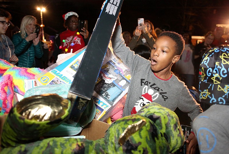 Staff photo by Erin O. Smith / Robert Lockett Jr., 10, pulls toys out of a box delivered at the second Santa Train stop on Derby Circle Tuesday, December 24, 2019 in Chattanooga, Tennessee. The Forgotten Child Fund, which gathered the toys and winter clothes for the Santa Train, was able to help 13,961 children this year and handed out over 3,000 coats, gloves and toboggans.