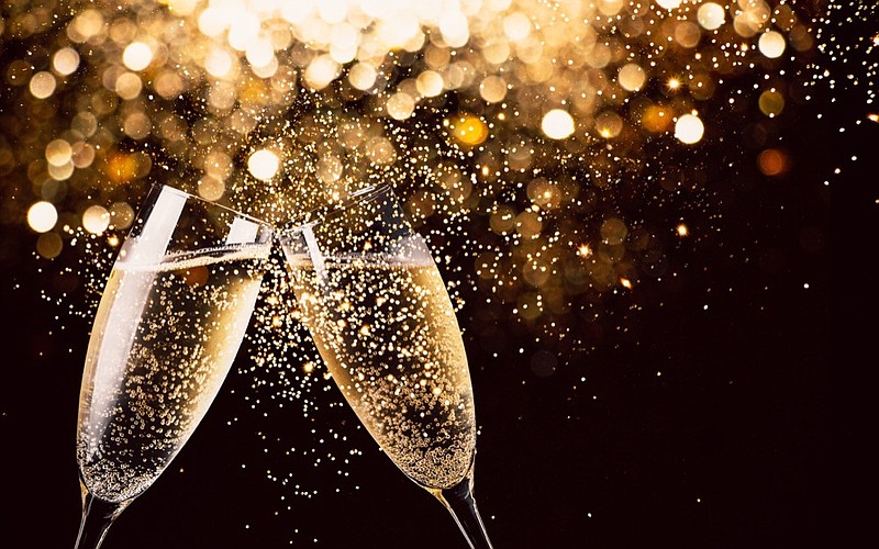 Two glasses of champagne toasting in the nigh with lights bokeh, glitter and sparks on the background new years new year tile new year's eve / Getty Images
