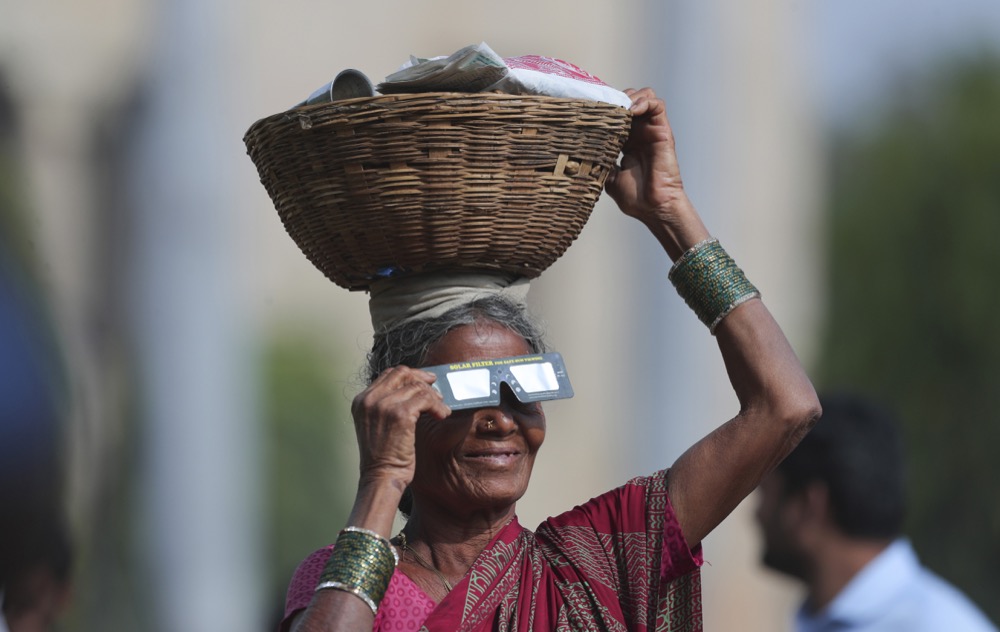 An Indian vendor women watch a partial solar eclipse in Hyderabad, India, Thursday, Dec. 26, 2019. The last solar eclipse of 2019 was witnessed in India along with several other countries. (AP Photo/Mahesh Kumar A.)